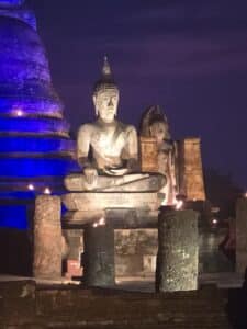 Statue de Bouddha illuminée à la nuit tombée dans les ruines du parc historique de Sukhothaï, Thaïlande.