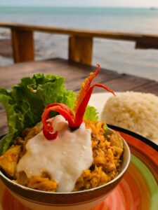 Amok cambodgien au crabe et lait de coco, décoré de piment et servi face à la mer.