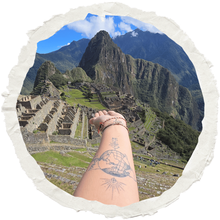 Bras tatoué tendu vers le Machu Picchu au Pérou, symbole de voyage et de liberté.