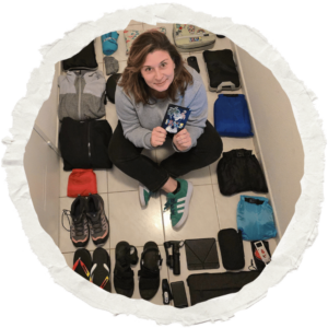 Magalie assise au milieu de ses affaires de voyage, préparant son sac à dos pour un long voyage solo autour du monde.