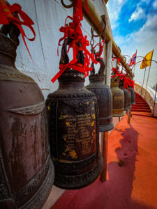 Rangée de cloches en bronze avec rubans rouges au Wat Saket, Bangkok.