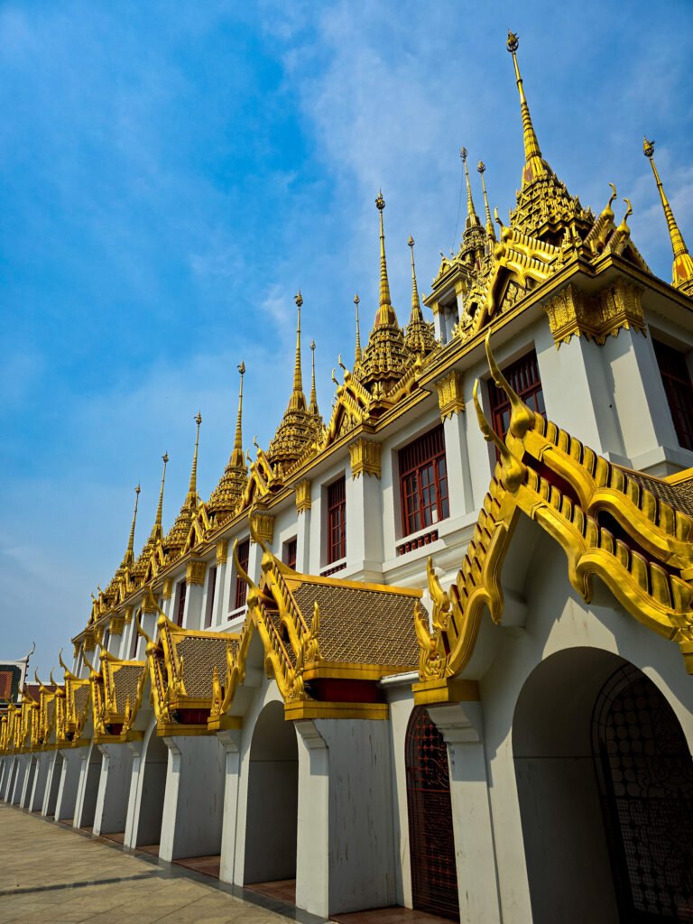 Le Loha Prasat de Bangkok, temple unique aux flèches dorées superposées sous un ciel bleu.
