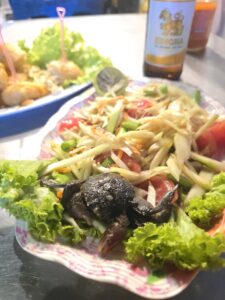 Assiette de som tam, salade de papaye verte thaïlandaise avec crabe, servie avec une bière Singha.