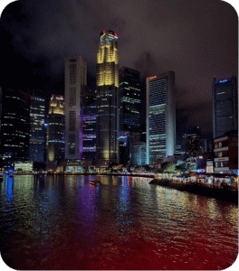 Gratte-ciels illuminés de Singapour la nuit, reflétés dans la rivière près de Boat Quay