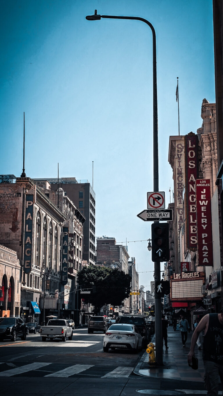 Vue en contre-plongée de Broadway à Los Angeles, bordée des enseignes verticales du Palace Theatre et d'anciens cinémas