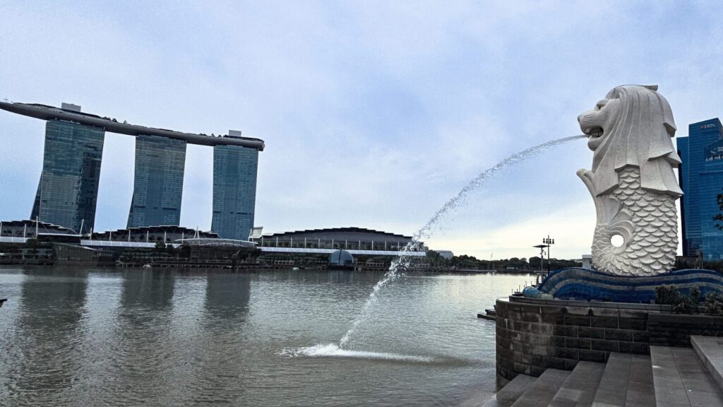 Le Merlion crachant de l'eau face aux trois tours de Marina Bay Sands, Singapour